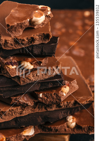 Stack of chocolate pieces with nuts close up on dark background 135539812