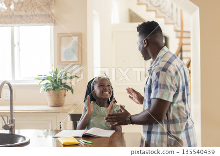 Father and daughter clapping hands together at home, enjoying playful bonding time 135540439