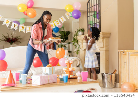 Celebrating birthday, African American mother and child with cupcakes and decorations Celebrating birthday, African American mother and child with cupcakes and decorations 135540454