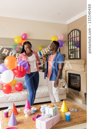 Celebrating at home, joyful couple holding balloons and enjoying birthday party 135540489