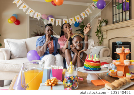 African American family celebrating birthday with cake and decorations at home 135540491