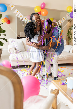African American family celebrating birthday at home with balloons and streamers African American family celebrating birthday at home with balloons and streamers 135540496