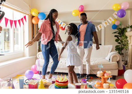 African American family celebrating birthday at home with balloons and cake African American family celebrating birthday at home with balloons and cake 135540516