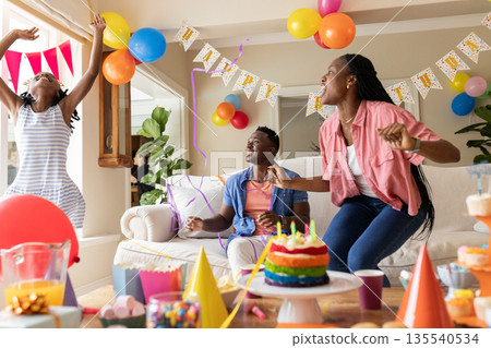 Joyful family dancing and laughing in colorful decorated living room for birthday Joyful family dancing and laughing in colorful decorated living room for birthday 135540534