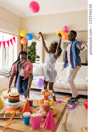 Dancing at home, family celebrating birthday with colorful decorations and cake Dancing at home, family celebrating birthday with colorful decorations and cake 135540539