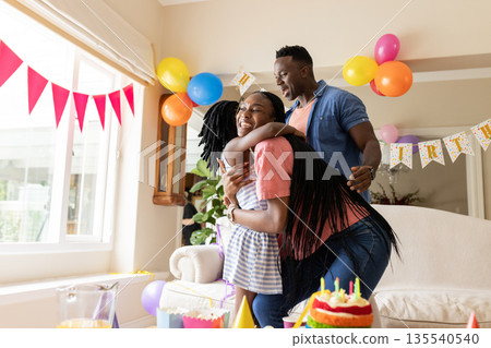 Celebrating birthday, joyful couple hugging in decorated living room with balloons Celebrating birthday, joyful couple hugging in decorated living room with balloons 135540540