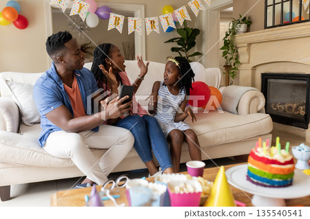 African American family celebrating birthday at home with cake and decorations African American family celebrating birthday at home with cake and decorations 135540541