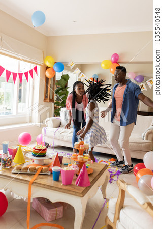 Family celebrating birthday at home, dancing joyfully with balloons and decorations 135540548