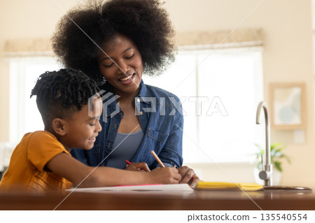 Mother and child drawing together at kitchen table, enjoying creative time Mother and child drawing together at kitchen table, enjoying creative time 135540554