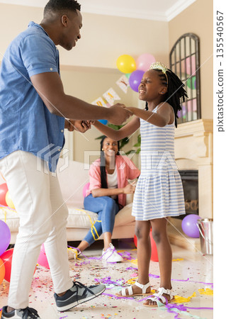 African American father and daughter dancing at home during birthday celebration African American father and daughter dancing at home during birthday celebration 135540567