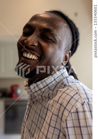 African American man smiling warmly at home, wearing checkered shirt African American man smiling warmly at home, wearing checkered shirt 135540601