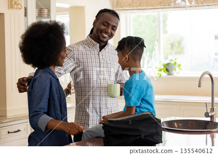 African American family enjoying morning together in kitchen, smiling and talking African American family enjoying morning together in kitchen, smiling and talking 135540612