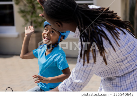 Father teaching son to ride bicycle, celebrating success with high five Father teaching son to ride bicycle, celebrating success with high five 135540642
