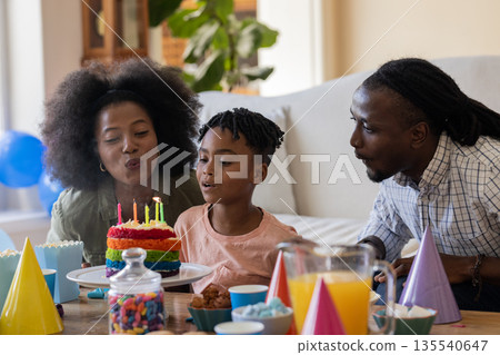 Celebrating birthday, African American family blowing out candles on colorful cake together Celebrating birthday, African American family blowing out candles on colorful cake together 135540647