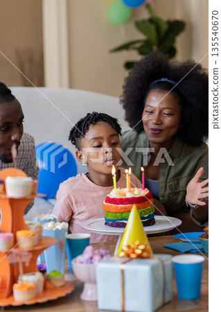 African American family celebrating birthday with child blowing out candles on cake 135540670