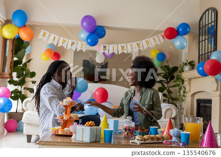 Celebrating birthday, African American couple with colorful balloons at party indoors Celebrating birthday, African American couple with colorful balloons at party indoors 135540676