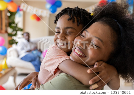 African American mother and child hugging joyfully at home during celebration African American mother and child hugging joyfully at home during celebration 135540691