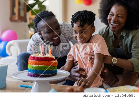 Celebrating birthday, joyful family with colorful cake and candles at home Celebrating birthday, joyful family with colorful cake and candles at home 135540695