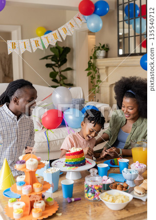 Celebrating birthday, happy family of three with cake and colorful home decorations 135540712