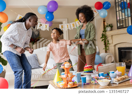 Celebrating child's birthday, African American family with colorful decorations at home Celebrating child's birthday, African American family with colorful decorations at home 135540727