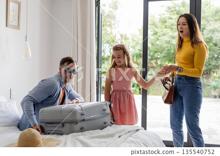 Family packing suitcase together at home, preparing for vacation with excitement Family packing suitcase together at home, preparing for vacation with excitement 135540752
