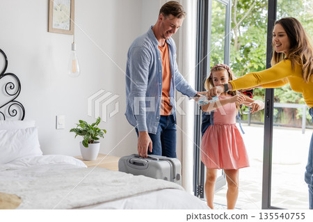 Family arriving at hotel room, unpacking suitcase, and enjoying vacation together Family arriving at hotel room, unpacking suitcase, and enjoying vacation together 135540755