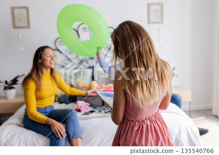 Family enjoying quality time at home, young girl using tablet on bed Family enjoying quality time at home, young girl using tablet on bed 135540766