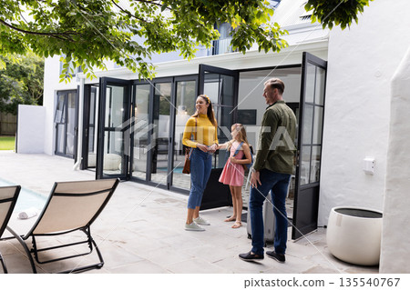 Exploring modern backyard patio, family discussing home features on sunny day 135540767