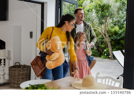 Family arriving home, mother holding teddy bear, daughter smiling, father following Family arriving home, mother holding teddy bear, daughter smiling, father following 135540786