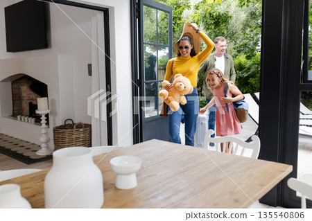 Family arriving home with luggage and teddy bear, smiling and excited Family arriving home with luggage and teddy bear, smiling and excited 135540806