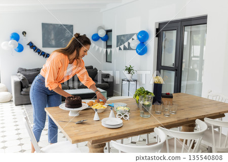 Woman preparing birthday table with cake and decorations at home celebration Woman preparing birthday table with cake and decorations at home celebration 135540808