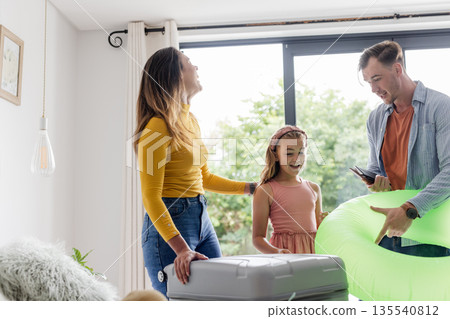 Family packing suitcase at home, preparing for vacation with inflatable pool toy 135540812