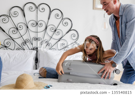 Father and daughter packing suitcase on bed, preparing for family vacation Father and daughter packing suitcase on bed, preparing for family vacation 135540815