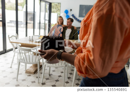 Bringing birthday cake, family celebrating together at home, creating joyful memories 135540891