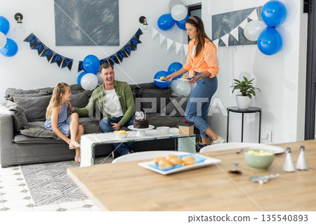 Celebrating birthday at home, family enjoying cake and decorations together 135540893