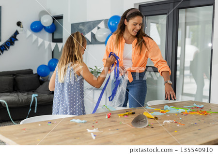 Mother and daughter cleaning up after birthday party at home, smiling together Mother and daughter cleaning up after birthday party at home, smiling together 135540910