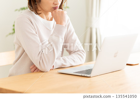 一位中年婦女擔心在家裡的客廳看電腦。 135541050