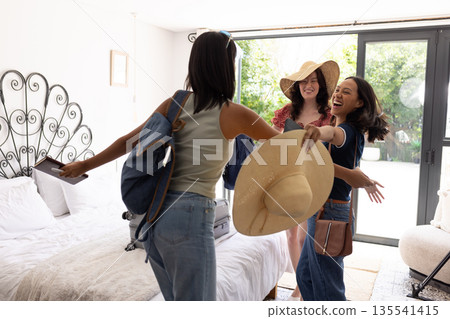 Welcoming each other with open arms, three young women share joyful reunion indoors Welcoming each other with open arms, three young women share joyful reunion indoors 135541415
