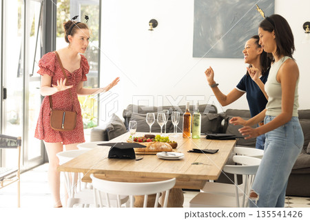 Three young women having lively conversation around dining table at home Three young women having lively conversation around dining table at home 135541426