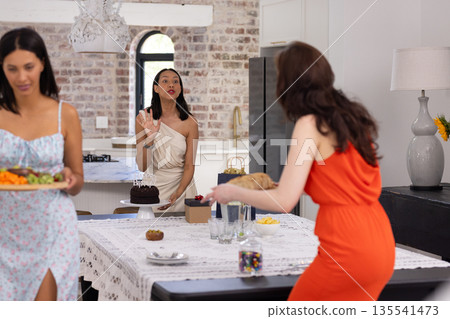 Carrying platter of colorful vegetables, two women in summer dresses prepare meal 135541473