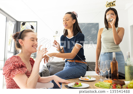 Celebrating indoors, three young women enjoy drinks and laughter together 135541488