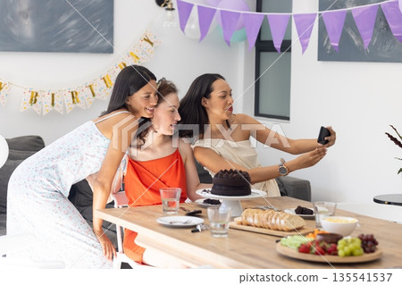 Taking selfie, three young women celebrate at birthday party indoors Taking selfie, three young women celebrate at birthday party indoors 135541537