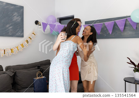 Hugging each other warmly, three young women celebrate birthday at home Hugging each other warmly, three young women celebrate birthday at home 135541564