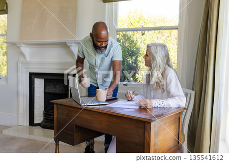 Man and woman discussing wedding plans at home with laptop and coffee mugs Man and woman discussing wedding plans at home with laptop and coffee mugs 135541612