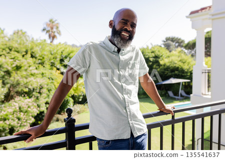 Smiling African American man enjoying sunny day on balcony, feeling relaxed Smiling African American man enjoying sunny day on balcony, feeling relaxed 135541637