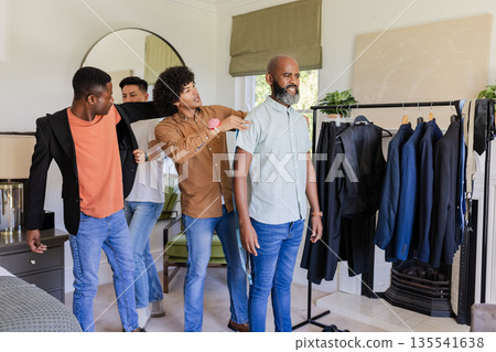 Friends helping groom try on outfits for wedding day, enjoying moment Friends helping groom try on outfits for wedding day, enjoying moment 135541638