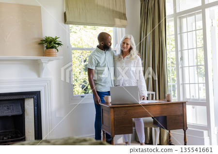 Couple embracing near desk with laptop, enjoying peaceful moment at home Couple embracing near desk with laptop, enjoying peaceful moment at home 135541661