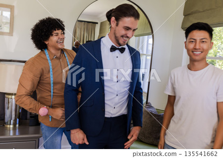 Groom in blue suit smiling with friends at home before wedding ceremony Groom in blue suit smiling with friends at home before wedding ceremony 135541662