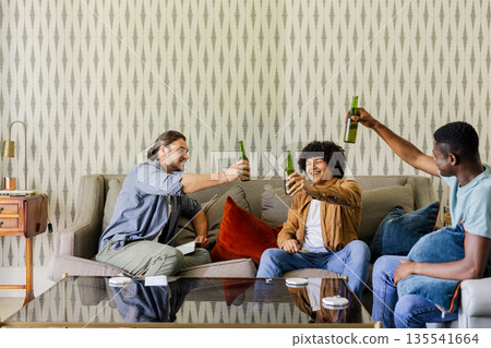 Friends celebrating with drinks on sofa, enjoying joyful moments together at home Friends celebrating with drinks on sofa, enjoying joyful moments together at home 135541664