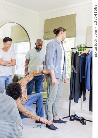 Groom fitting suit with friends, enjoying preparations for wedding day at home Groom fitting suit with friends, enjoying preparations for wedding day at home 135541668